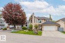 Stucco exterior with a two-car garage, pitched shingle roof, mature front yard tree, and a concrete driveway - 342 O'Connor Close, Edmonton, AB  - Outdoor With Facade 