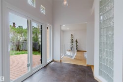 Spacious entry area with dark tile flooring, a curved glass block wall, and high ceilings - 