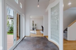 Spacious entryway featuring dark tile flooring and a curved glass block wall - 
