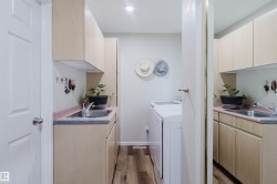 Utility area featuring wood-finish flooring and light-toned cabinetry - 