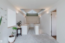 Upper-level landing featuring a vaulted ceiling with skylight, recessed lighting, wall sconces, and light wood-finish railings - 