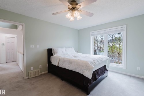 Carpeted room featuring a large window, a ceiling fan with integrated lighting, and light-toned wall paint - 342 O'Connor Close, Edmonton, AB - Indoor Photo Showing Bedroom