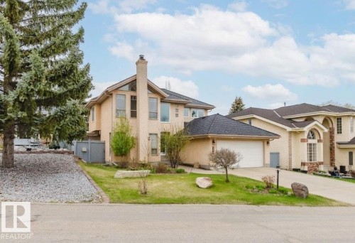 Stucco exterior with a prominent brick chimney, arched and rectangular windows, an attached two-car garage, and a concrete driveway - 342 O'Connor Close, Edmonton, AB - Outdoor With Facade