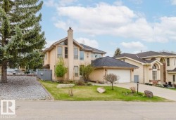 Stucco exterior with a prominent brick chimney, arched and rectangular windows, an attached two-car garage, and a concrete driveway - 