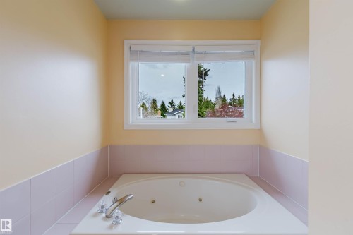 Built-in jetted tub with chrome fixtures, tiled surround, and upper wall in a light neutral tone - 342 O'Connor Close, Edmonton, AB - Indoor Photo Showing Bathroom
