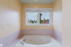Built-in jetted tub with chrome fixtures, tiled surround, and upper wall in a light neutral tone - 