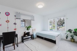 Bright room featuring white walls, a large window with blinds, and light-colored carpeting - 