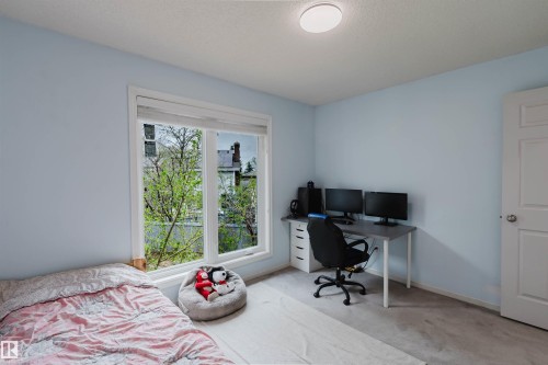 Spacious room featuring a large window, light blue wall paint, light-toned carpeting, and a white paneled door - 342 O'Connor Close, Edmonton, AB - Indoor Photo Showing Bedroom