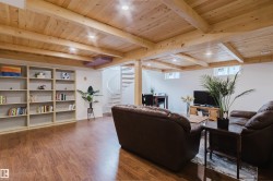 Spacious lower level featuring wood-finish flooring and an exposed wood beam ceiling with recessed lighting - 