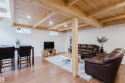 Finished lower level featuring wood-finish flooring, exposed wood beam ceiling, recessed lighting, and a partial wood column - 