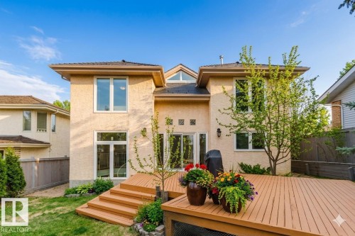 Rear stucco exterior featuring a tiered wood-finish deck with integrated planters, multiple large windows, and sliding glass doors - 342 O'Connor Close, Edmonton, AB - Outdoor