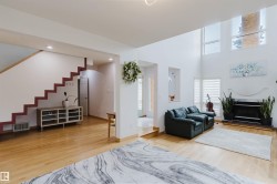 Spacious living area featuring high ceilings, large windows, and light wood-finish flooring - 