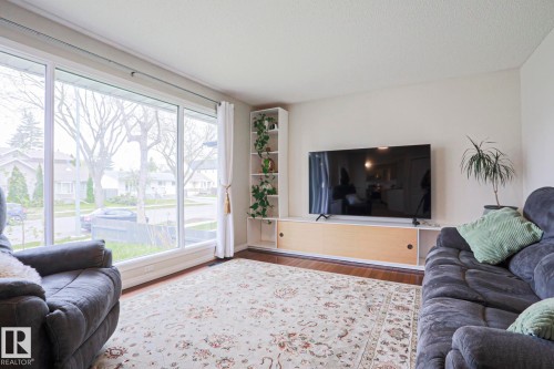 Room featuring large picture windows, wood-finish flooring, and a built-in media console with open shelving - 9523 151 Street, Edmonton, AB - Indoor Photo Showing Living Room