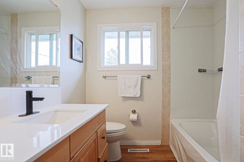 Bathroom vanity with a white countertop and integrated sink, featuring a matte black single-handle faucet - 9523 151 Street, Edmonton, AB - Indoor Photo Showing Bathroom