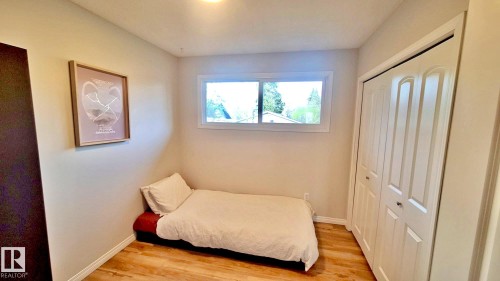 Bright bedroom with wood-finish flooring, a double-panel closet, and a horizontal window - 9523 151 Street, Edmonton, AB - Indoor Photo Showing Bedroom