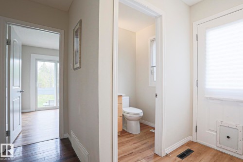 Entryway featuring wood-finish flooring, a white paneled door with privacy blinds, and access to a powder room - 9523 151 Street, Edmonton, AB - Indoor Photo Showing Bathroom