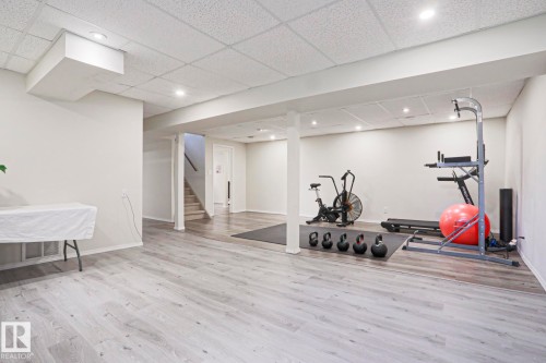 Spacious finished lower level featuring light wood-finish flooring, recessed lighting, and a drop ceiling - 9523 151 Street, Edmonton, AB - Indoor Photo Showing Gym Room