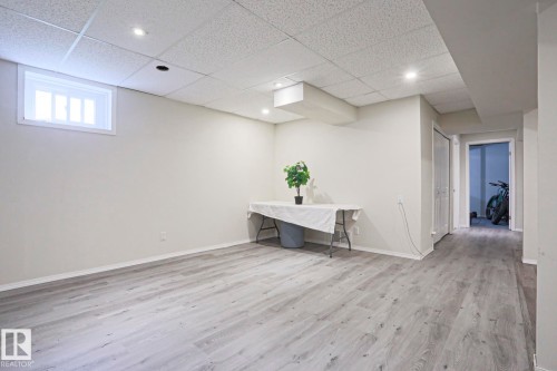 Spacious room featuring wood-finish flooring, a drop ceiling with recessed lighting, and a white-framed window - 9523 151 Street, Edmonton, AB - Indoor Photo Showing Other Room