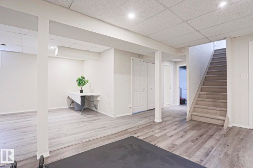 Spacious finished basement featuring light wood-finish flooring, recessed lighting, and a carpeted staircase - 9523 151 Street, Edmonton, AB - Indoor Photo Showing Other Room