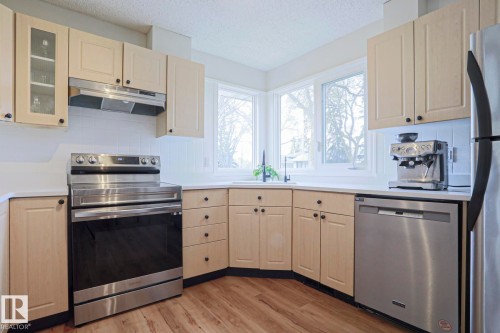 Kitchen featuring light-toned cabinetry, stainless steel appliances, and wood-finish flooring - 9523 151 Street, Edmonton, AB - Indoor Photo Showing Kitchen