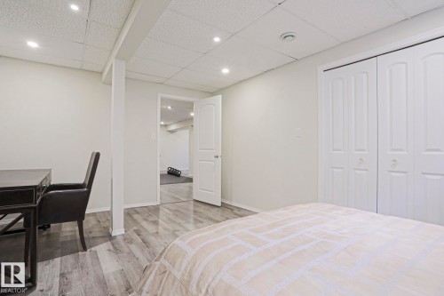 White interior room featuring gray wood-finish flooring, recessed ceiling lighting, and a white bi-fold closet - 9523 151 Street, Edmonton, AB - Indoor Photo Showing Bedroom