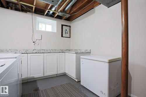 Laundry area featuring white cabinetry, light-colored countertops, a single window, and exposed ceiling joists - 9523 151 Street, Edmonton, AB - Indoor Photo Showing Laundry Room