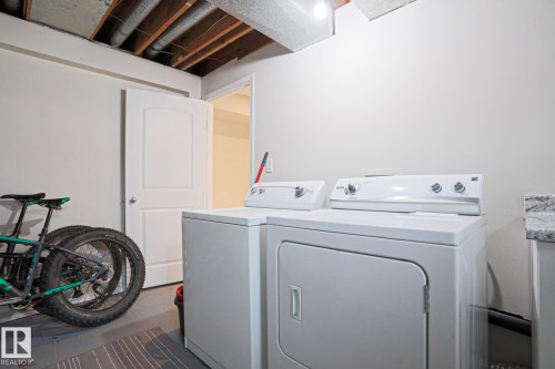 Dedicated laundry area featuring a white washer and dryer set, white walls, and a visible wood-beamed ceiling - 9523 151 Street, Edmonton, AB - Indoor Photo Showing Laundry Room