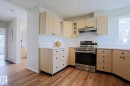 Kitchen featuring wood-finish flooring, light-toned cabinetry with dark hardware, solid surface countertops, and a stainless steel range with overhead ventilation - 9523 151 Street, Edmonton, AB  - Indoor Photo Showing Kitchen 