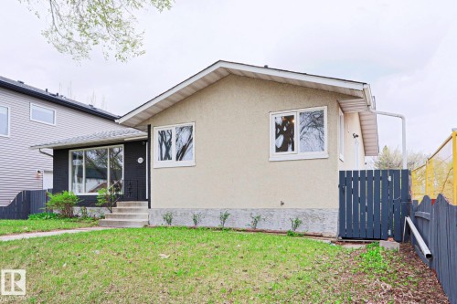 Ranch-style exterior featuring a stucco facade, dark accent siding, and white-framed windows - 9523 151 Street, Edmonton, AB - Outdoor