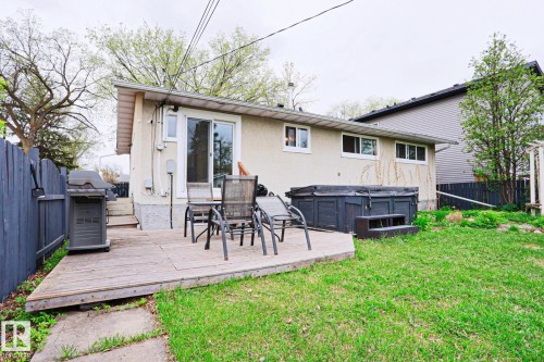 Rear exterior showcasing a wooden deck, a hot tub, and a grassy lawn - 9523 151 Street, Edmonton, AB - Outdoor With Deck Patio Veranda