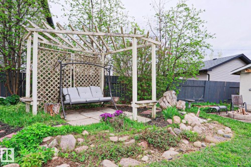 Backyard oasis featuring a pergola structure with lattice detailing, concrete patio, built-in benches, and rock garden landscaping - 9523 151 Street, Edmonton, AB - Outdoor