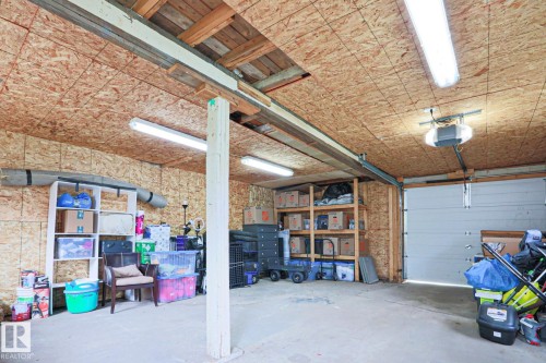 Garage space with a concrete floor, exposed oriented strand board walls and ceiling, and overhead fluorescent lighting - 9523 151 Street, Edmonton, AB - Indoor Photo Showing Garage