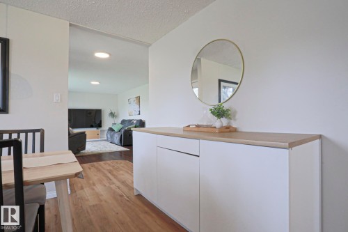 Dining area featuring a modern white console with a wood-finish countertop, wood-finish flooring, and recessed ceiling lighting - 9523 151 Street, Edmonton, AB - Indoor