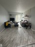 Spacious living area featuring light-toned wood-finish flooring and a white painted brick accent wall - 205 10136 160 Street, Edmonton, AB  - Indoor Photo Showing Living Room 
