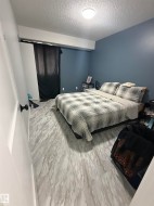 Spacious room featuring light wood-finish flooring, a ceiling-mounted light fixture, and a deep blue accent wall - 