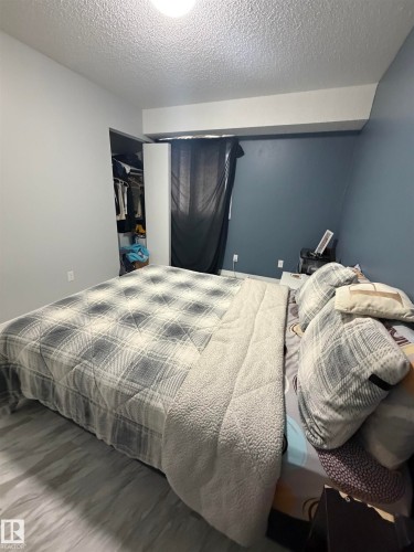 Room featuring light wood-finish flooring, a built-in closet with shelving, and a window with dark drapery - 205 10136 160 Street, Edmonton, AB - Indoor Photo Showing Bedroom