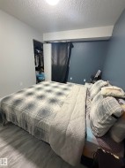 Room featuring light wood-finish flooring, a built-in closet with shelving, and a window with dark drapery - 