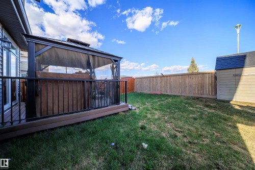 Rear yard featuring an elevated deck with a screened gazebo, a wooden privacy fence, a storage shed, and mature tree landscaping - 9651 229 Street, Edmonton, AB - Outdoor
