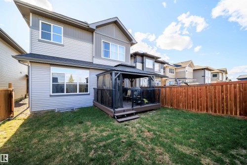 Rear exterior featuring a grass lawn, wood fencing, and a built-in deck with a covered gazebo - 9651 229 Street, Edmonton, AB - Outdoor With Exterior
