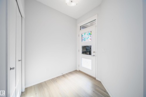 Entryway featuring a white door with decorative stained-glass panels and transom window, light wood-finish flooring, a flush-mount ceiling light, and white walls - 9651 229 Street, Edmonton, AB - Indoor Photo Showing Other Room