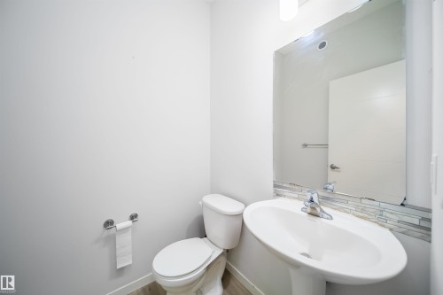 Pedestal sink with chrome faucet, large frameless mirror, and mosaic tile backsplash - 9651 229 Street, Edmonton, AB - Indoor Photo Showing Bathroom