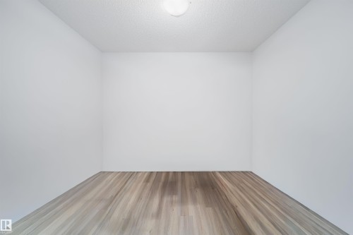 Room featuring wood-finish flooring, white walls, and a ceiling-mounted light fixture - 9651 229 Street, Edmonton, AB - Indoor Photo Showing Other Room