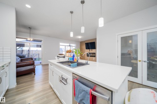 Kitchen island with a white countertop and integrated sink - 9651 229 Street, Edmonton, AB - Indoor Photo Showing Kitchen With Double Sink
