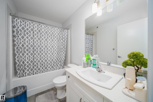 Bathroom featuring a white vanity with an integrated sink, polished chrome faucet, and a large mirror with contemporary light fixtures - 9651 229 Street, Edmonton, AB - Indoor Photo Showing Bathroom