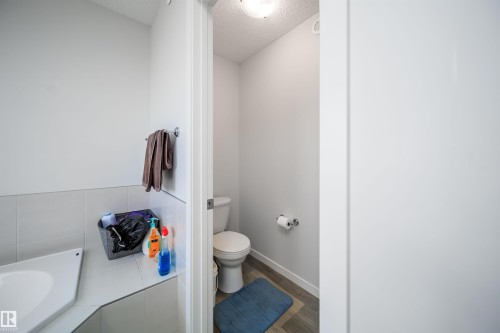 Bathroom featuring a corner bathtub, white wall tiling, and a separate commode area with wood-finish flooring - 9651 229 Street, Edmonton, AB - Indoor Photo Showing Bathroom