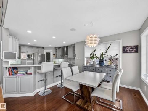 Open-concept kitchen and dining area featuring rich wood-finish flooring, light grey cabinetry, stainless steel appliances, and recessed lighting - 1062 Tory Road, Edmonton, AB - Indoor Photo Showing Dining Room