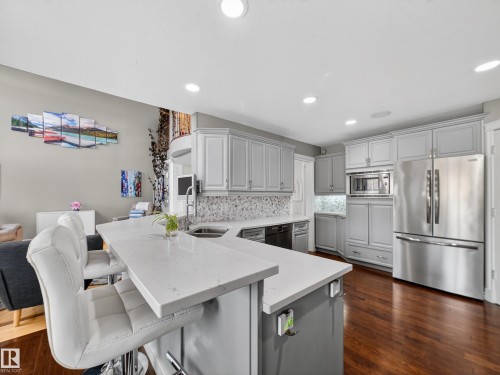 Kitchen featuring light gray cabinetry, stainless steel appliances, and a mosaic tile backsplash - 1062 Tory Road, Edmonton, AB - Indoor Photo Showing Other Room