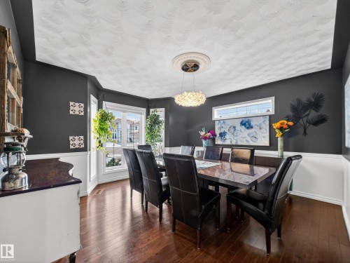 Dining area featuring dark wood-finish flooring, white wainscoting, and large bay windows - 1062 Tory Road, Edmonton, AB - Indoor Photo Showing Dining Room