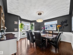 Dining area featuring dark wood-finish flooring, white wainscoting, and large bay windows - 
