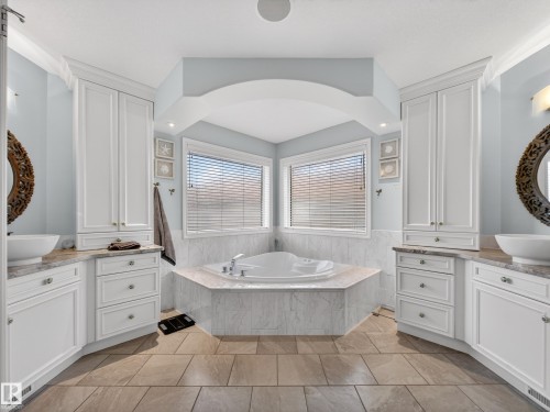 Corner soaking tub with dual windows, flanked by twin vanity stations - 1062 Tory Road, Edmonton, AB - Indoor Photo Showing Bathroom